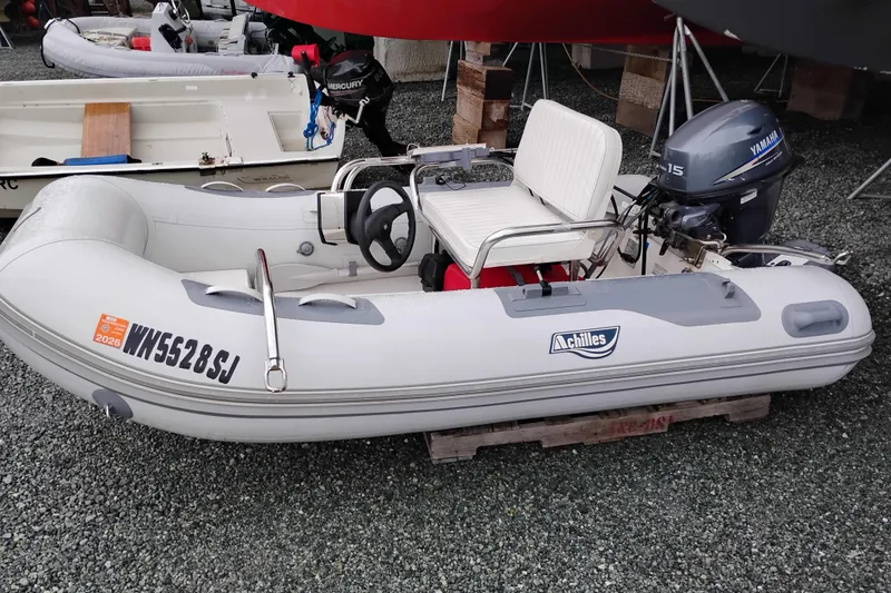 Slide: The Image of Inflatable Achilles boat with Yamaha motor, parked on gravel. - 53