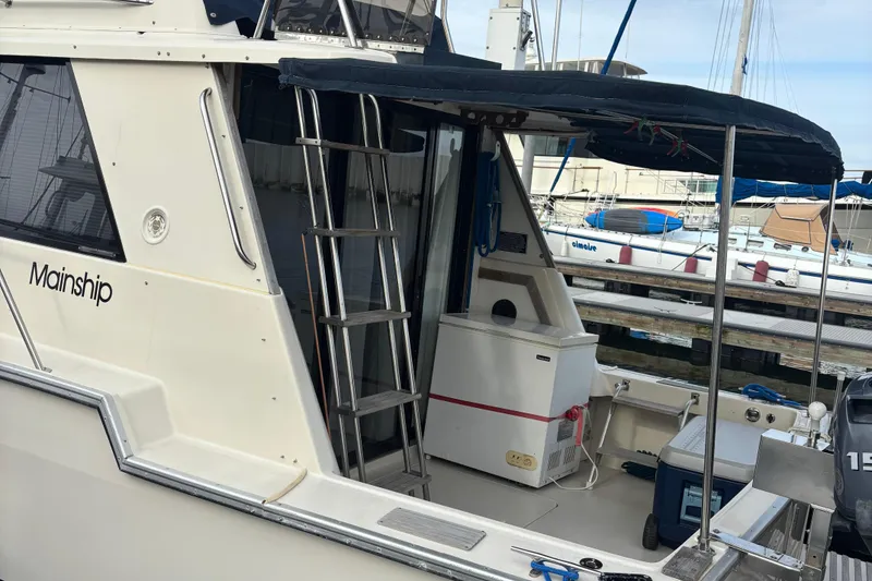 Slide: The Image of 1985 Mainship 34 III boat docked, featuring a covered deck and ladder. - 6