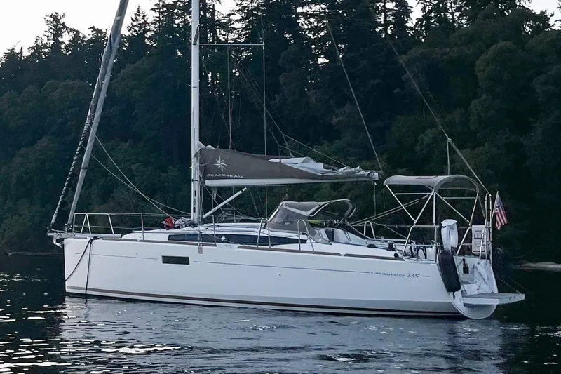 The Image of 2016 Jeanneau Sun Odyssey 349 sailboat anchored near forested shoreline. - 1