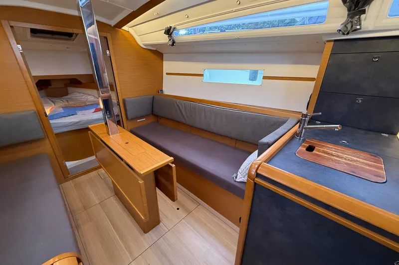 Slide: The Image of Interior of 2016 Jeanneau Sun Odyssey 349 sailboat, featuring cozy seating and compact kitchen area. - 10
