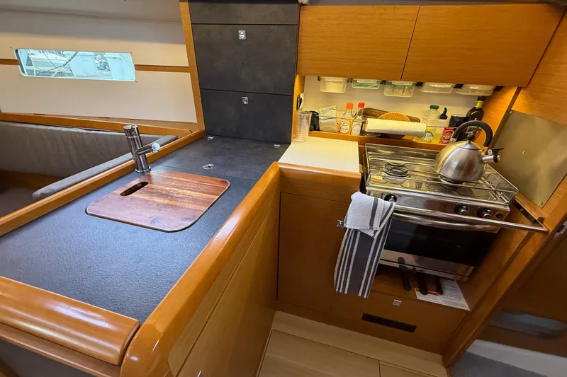 Slide: The Image of Compact kitchen in 2016 Jeanneau Sun Odyssey 349 sailboat with stove, sink, and storage. - 16