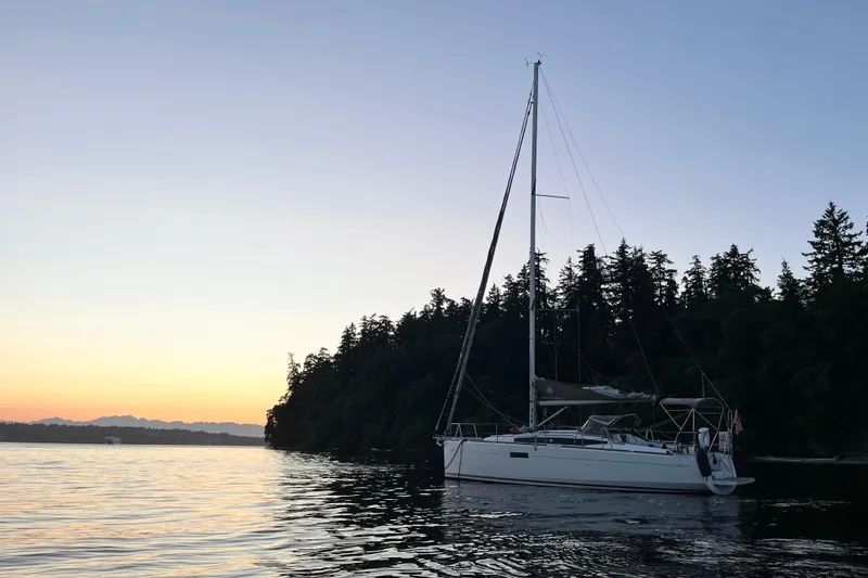Slide: The Image of 2016 Jeanneau Sun Odyssey 349 sailboat at sunset near forested shoreline. - 39