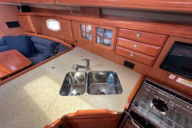 Slide: The Image of 2008 Hunter 36 yacht interior kitchen with sink, stove, and wooden cabinetry. - 48
