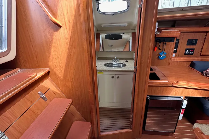 Slide: The Image of 2008 Hunter 36 yacht interior with wooden cabinetry, sink, and compact kitchen area. - 56