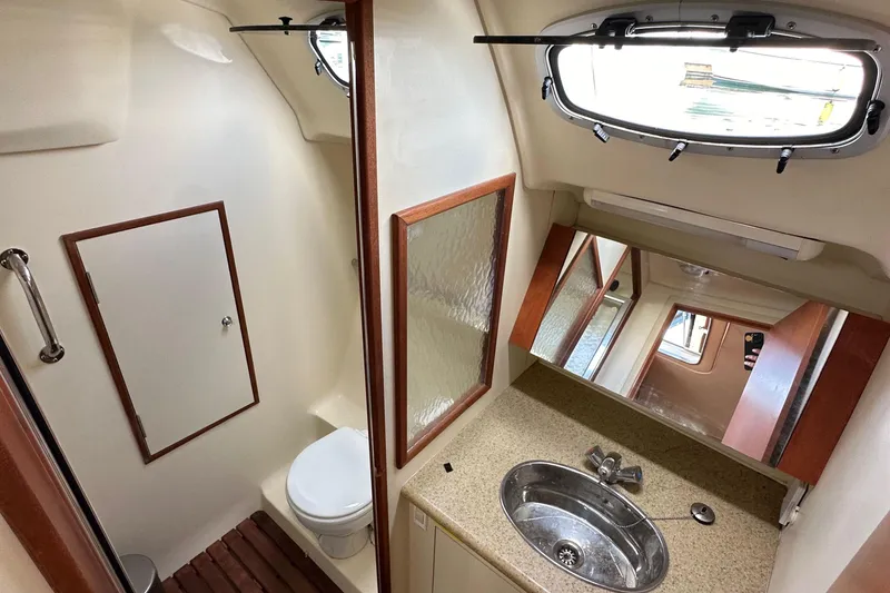 Slide: The Image of 2008 Hunter 36 yacht bathroom with sink, toilet, mirror, and porthole window. - 57