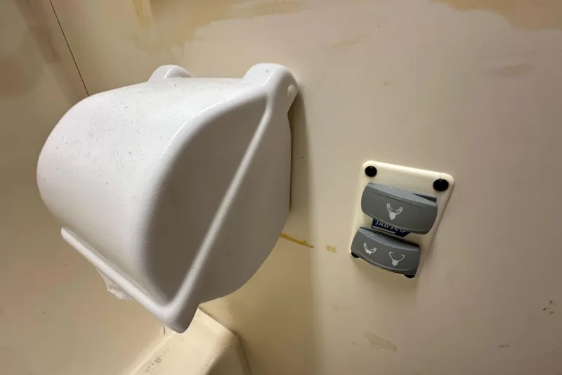 Slide: The Image of Wall-mounted toilet paper holder and flush buttons in a 2008 Hunter 36 boat bathroom. - 60