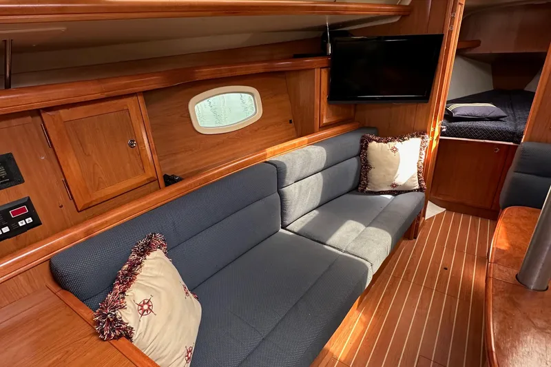 Slide: The Image of 2008 Hunter 36 yacht interior with cozy seating, wooden cabinetry, and a mounted TV. - 73