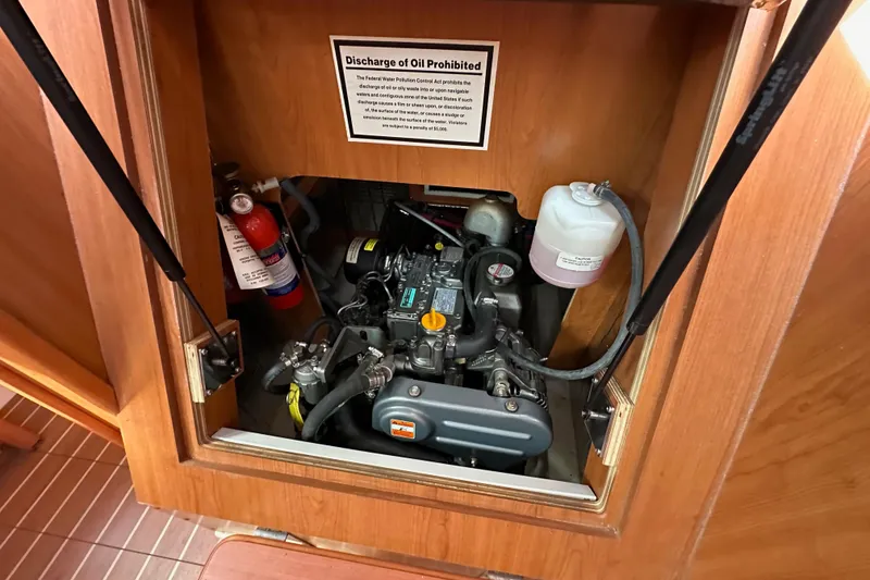 Slide: The Image of Engine compartment of a 2008 Hunter 36 sailboat with fire extinguisher and oil discharge warning. - 84