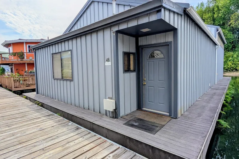 Slide: The Image of Historic 1801 custom boathouse on calm water, surrounded by greenery and small boats. - 1