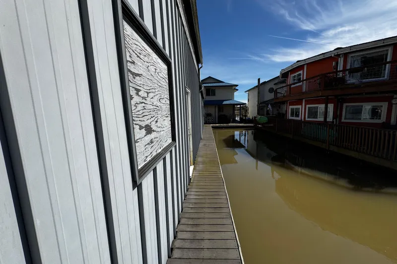 Slide: The Image of Gray boathouse exterior with door, number 46, and docked boat nearby. - 3