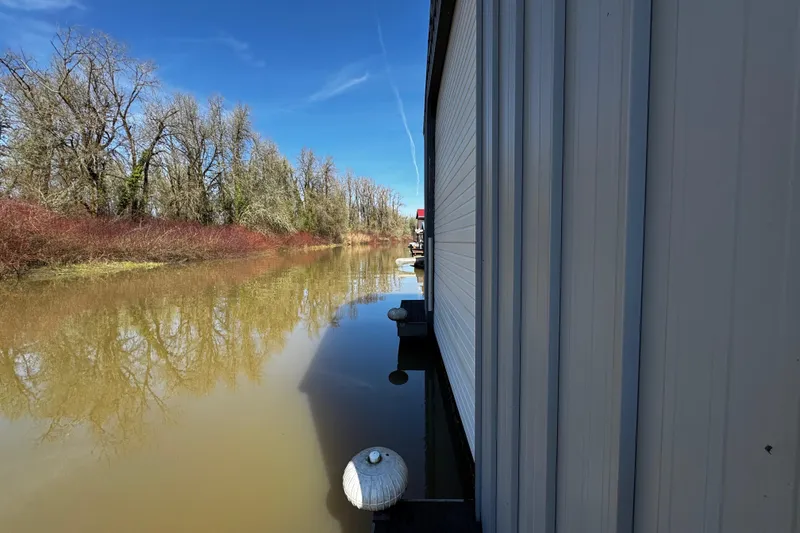Slide: The Image of Historic boathouse with wooden walkway beside calm water, under a clear blue sky. - 4