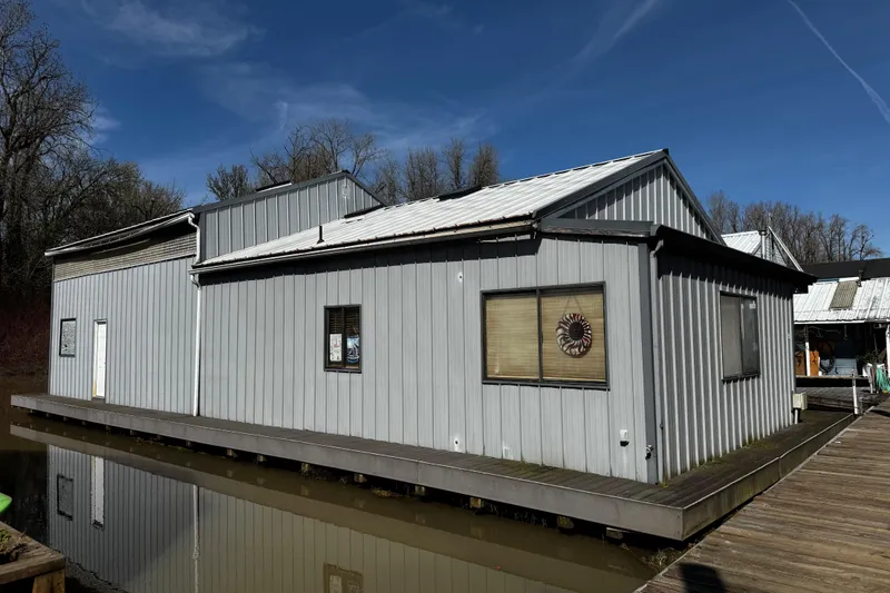 Slide: The Image of Boathouse on calm river with trees reflecting in water, clear blue sky above. - 5