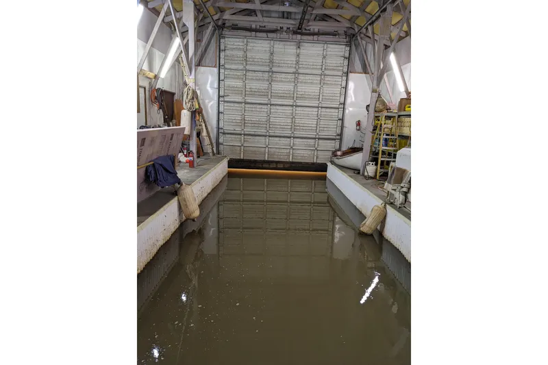 Slide: The Image of Gray boathouse on water with metal roof, surrounded by trees and clear blue sky. - 6