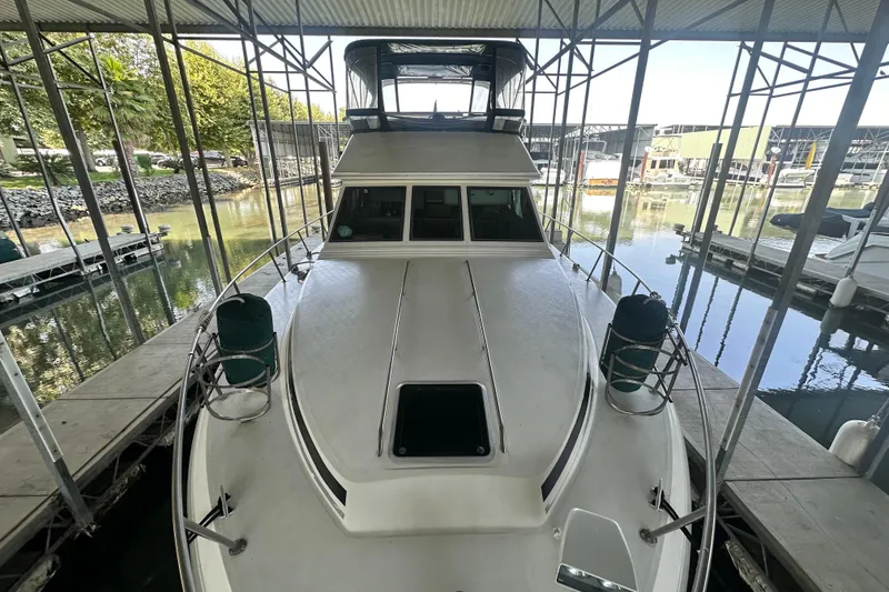Slide: The Image of 1990 Sea Ray 380 Aft Cabin yacht docked in a marina under a covered structure. - 13