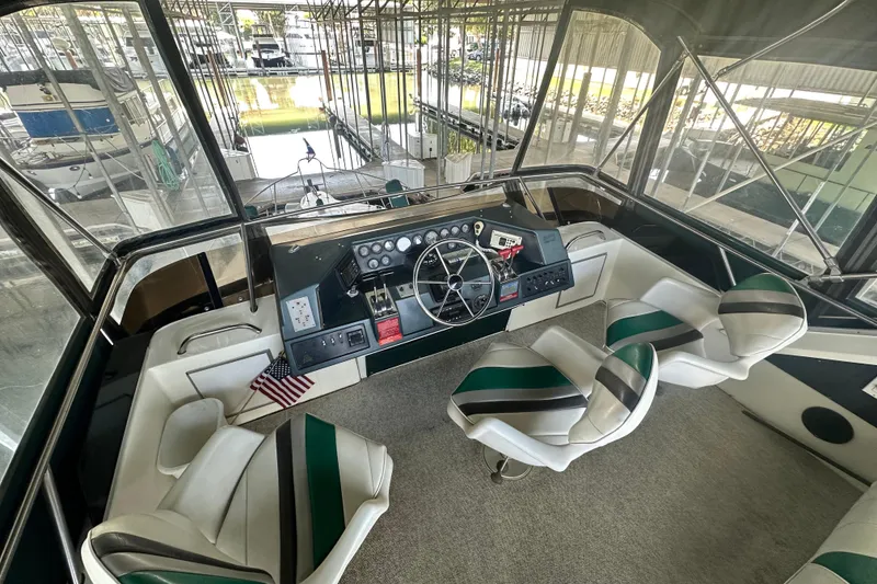 Slide: The Image of 1990 Sea Ray 380 Aft Cabin helm with steering wheel, gauges, and seating in marina. - 21