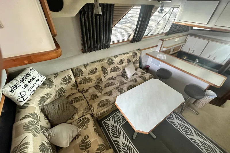 Slide: The Image of 1990 Sea Ray 380 Aft Cabin interior with patterned sofa, table, and kitchenette. - 32