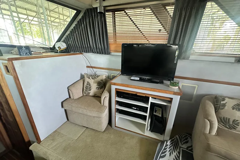 Slide: The Image of 1990 Sea Ray 380 Aft Cabin interior with TV, cozy seating, and nautical decor. - 35