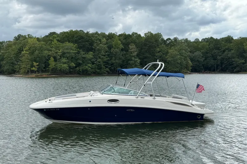 The Image of 2009 Sea Ray 280 Sundeck boat on a lake with forested shoreline. - 1