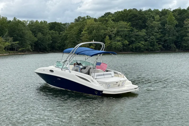Slide: The Image of 2009 Sea Ray 280 Sundeck boat on a lake with American flag, surrounded by trees. - 3