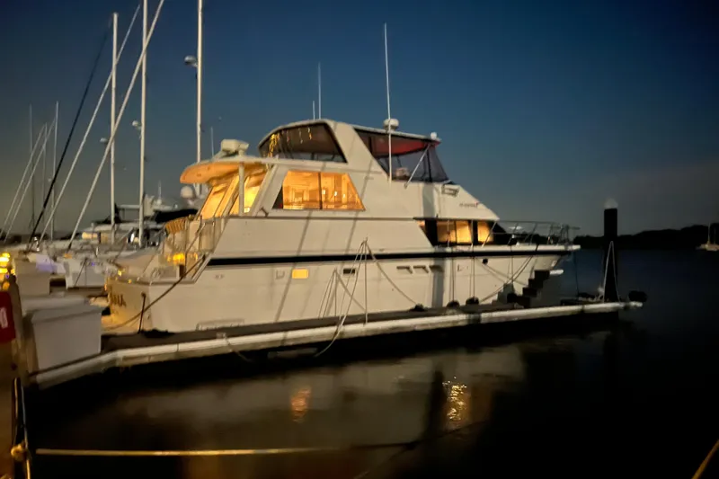 The Image of 1991 Hatteras 52 Cockpit Motor Yacht docked at night, illuminated interior. - 0