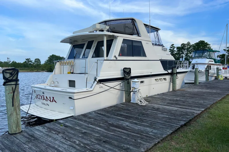 Slide: The Image of 1991 Hatteras 52 Cockpit Motor Yacht docked by a wooden pier. - 1