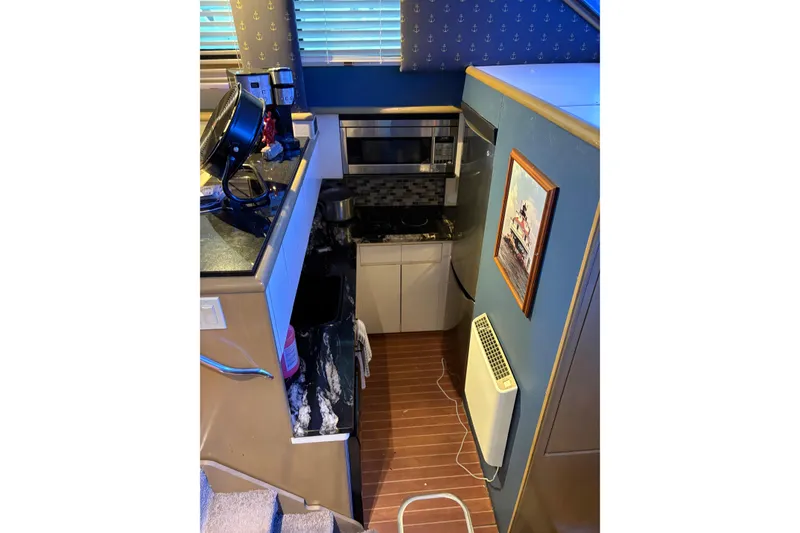 Slide: The Image of Interior of 1991 Hatteras 52 Cockpit Motor Yacht with compact kitchen and nautical decor. - 16