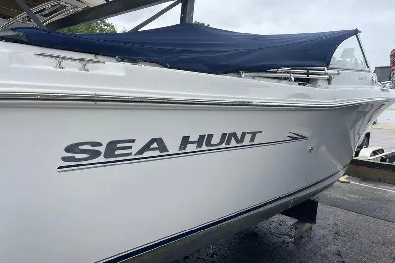 Slide: The Image of 2009 Sea Hunt Escape 220 LE boat with blue cover, docked on a trailer. - 12