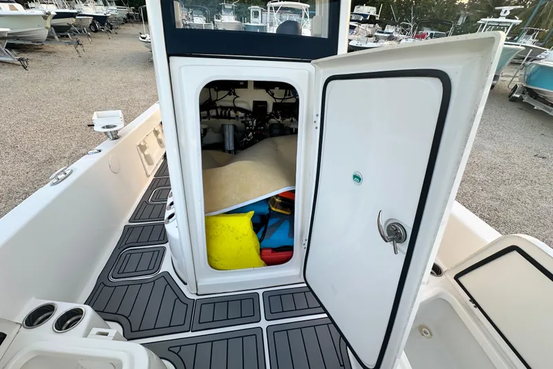 Slide: The Image of 2022 World Cat 235 CC boat interior storage compartment with open door, showing equipment inside. - 12