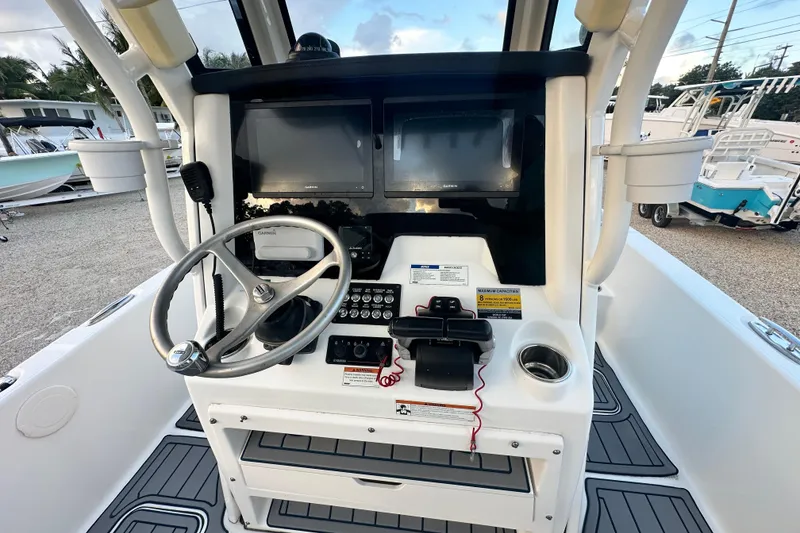 Slide: The Image of 2022 World Cat 235 CC boat console with steering wheel and navigation screens. - 14