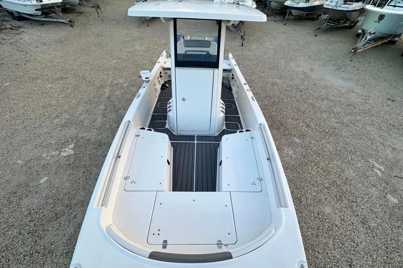 Slide: The Image of 2022 World Cat 235 CC boat, top view, spacious deck, sleek design, parked on gravel. - 9