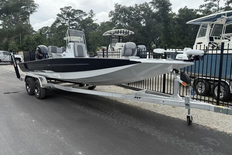 Slide: The Image of 2026 Xpress H22B boat on trailer, parked outdoors near other boats. - 2