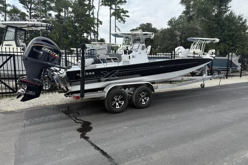 Slide: The Image of 2026 Xpress H22B boat on trailer, parked outdoors near other boats. - 3
