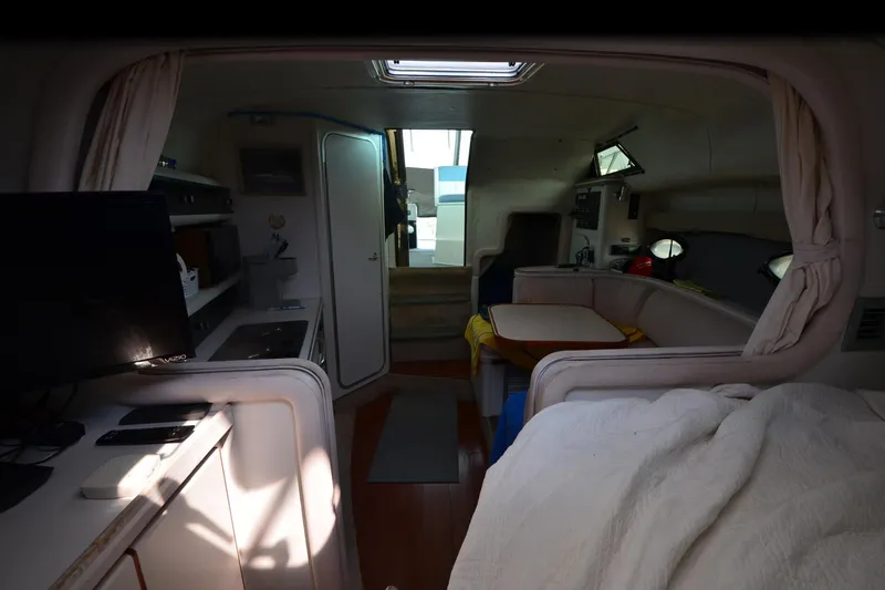 Slide: The Image of Interior of a 1990 Slick Craft 310 SC boat, featuring cozy seating and a compact kitchen area. - 19
