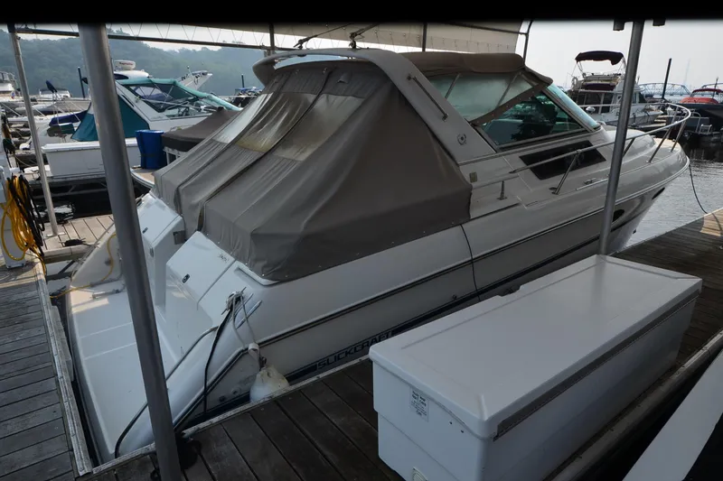 Slide: The Image of 1990 Slick Craft 310 SC boat docked with covered cabin, surrounded by other boats. - 4