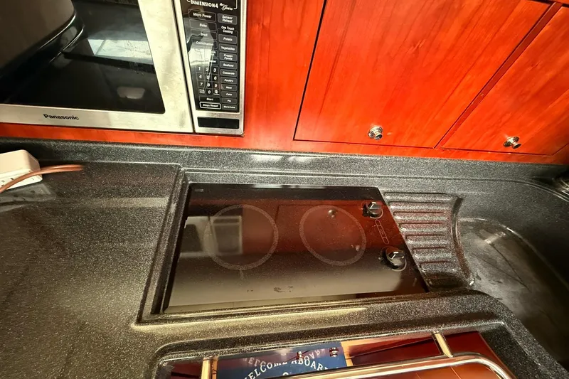 Slide: The Image of 2005 Chris-Craft Roamer 40 kitchen with stove, microwave, and wooden cabinets. - 38