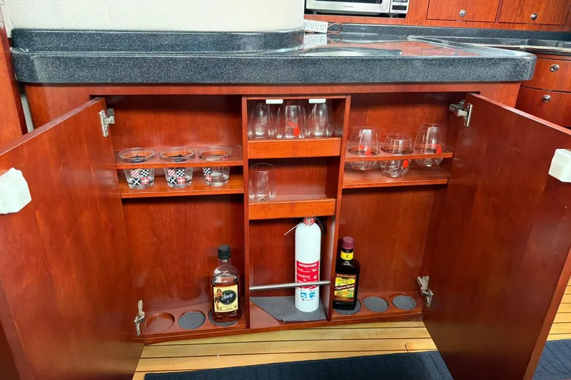 Slide: The Image of 2005 Chris-Craft Roamer 40 yacht cabinet with glassware, bottles, and fire extinguisher. - 60