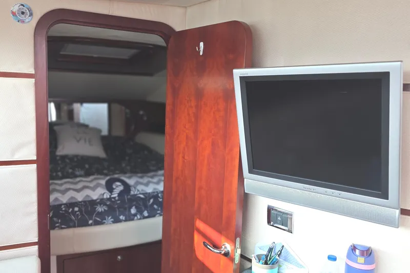 Slide: The Image of 2005 Chris-Craft Roamer 40 interior with bed, TV, and wooden door. - 61