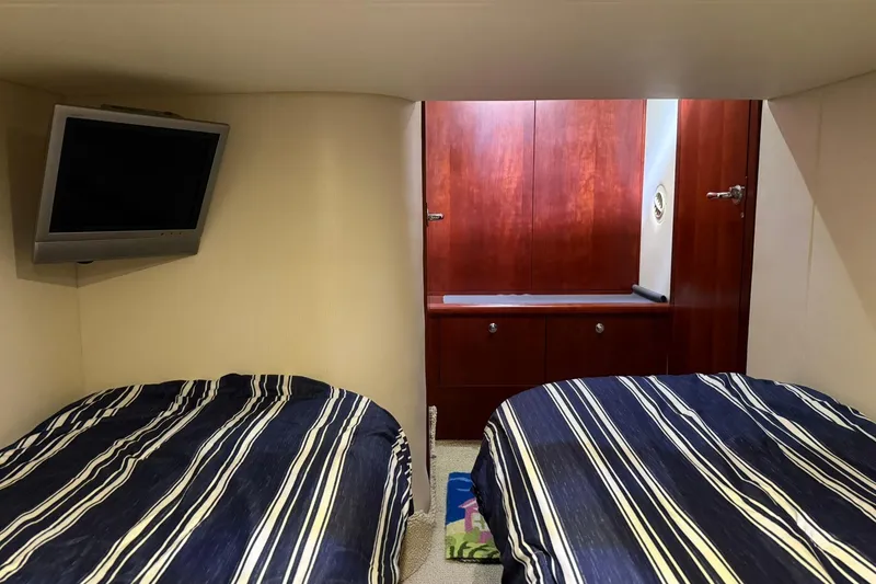Slide: The Image of 2005 Chris-Craft Roamer 40 cabin with twin beds, striped bedding, and wall-mounted TV. - 67