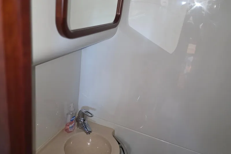 Slide: The Image of Bathroom sink area on 2005 Chris-Craft Roamer 40 yacht, featuring a mirror and faucet. - 68