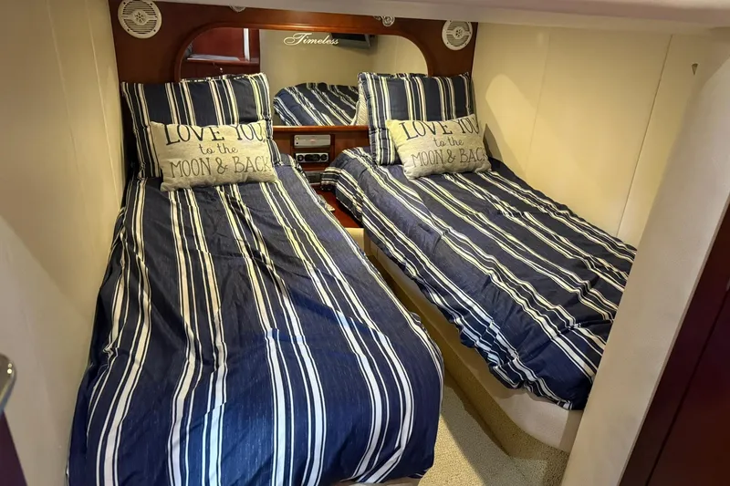 Slide: The Image of Twin beds with striped bedding in 2005 Chris-Craft Roamer 40 cabin, featuring decorative pillows. - 69