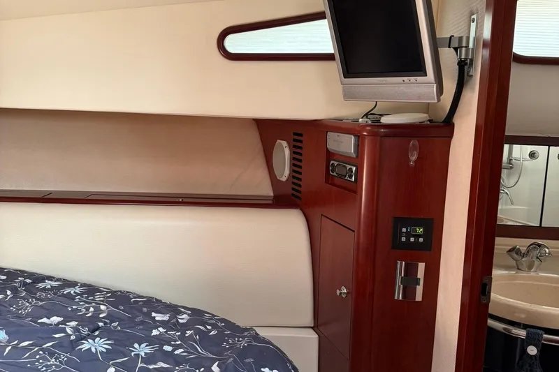 Slide: The Image of Luxurious 2005 Chris-Craft Roamer 40 cabin interior with TV, wood paneling, and floral bedding. - 70