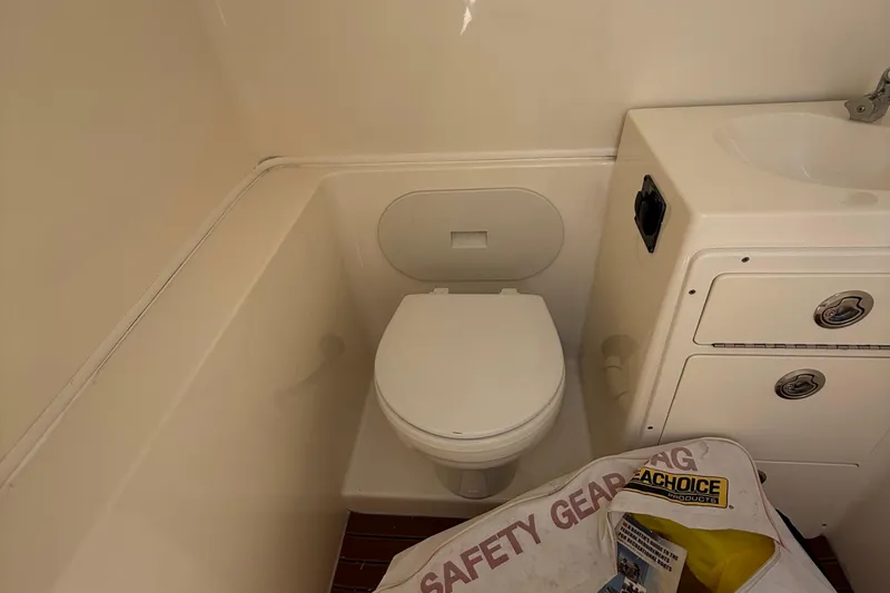 Slide: The Image of 2015 Cobia 296 Center Console boat bathroom with toilet and safety gear bag. - 23