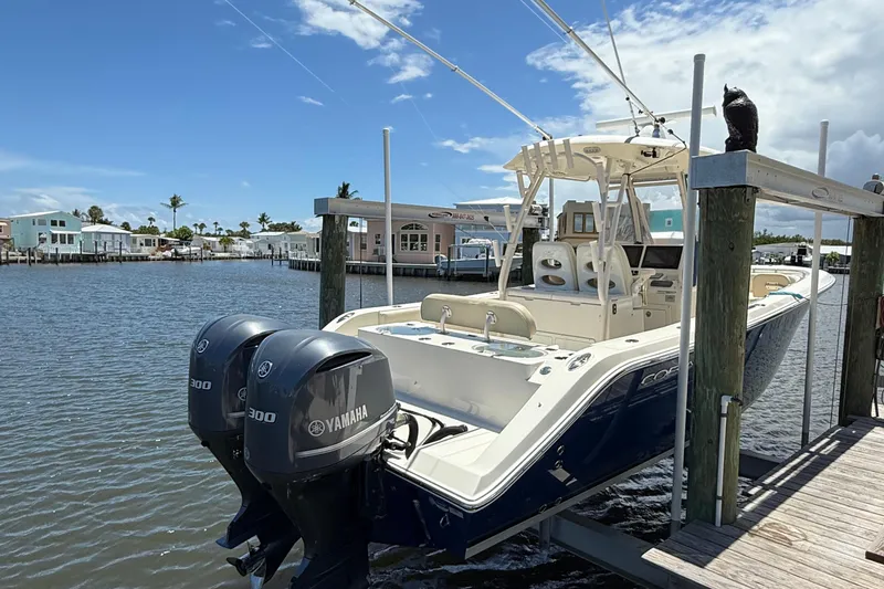 Slide: The Image of 2015 Cobia 296 Center Console boat with twin Yamaha 300 engines docked by waterfront homes. - 3