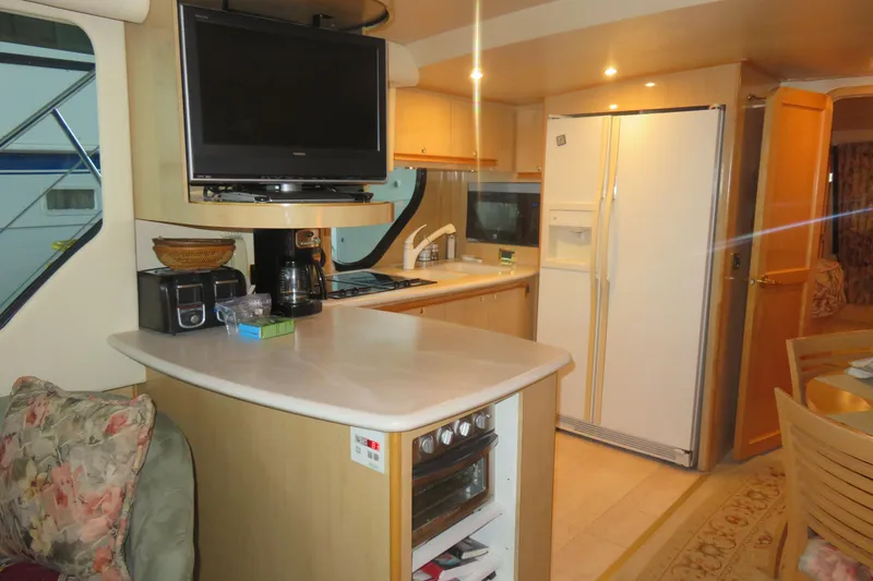 Slide: The Image of Interior of 2000 Bluewater Yachts 5800, featuring kitchen with appliances and dining area. - 15