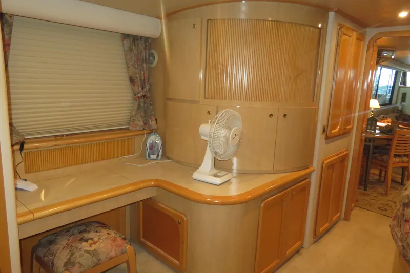 Slide: The Image of Interior of 2000 Bluewater Yachts 5800, featuring a cozy desk area with fan and seating. - 20