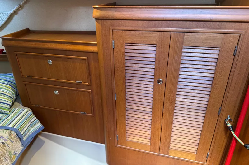 Slide: The Image of Wooden cabinetry inside a 2004 Island Packet 420 sailboat, featuring drawers and a louvered door. - 27