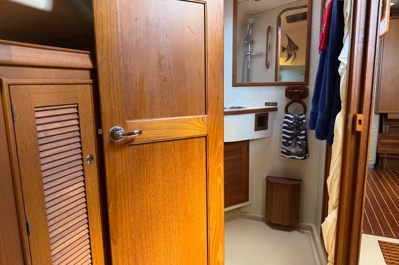 Slide: The Image of Interior of 2004 Island Packet 420 sailboat, featuring wooden cabinetry and bathroom area. - 28