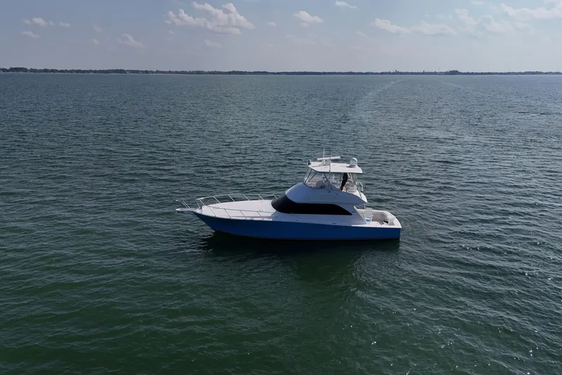 Slide: The Image of 2003 Viking 48 Convertible boat interior with white seating and dock view. - 11