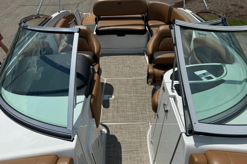 Slide: The Image of 2024 Crownline Eclipse E235 boat interior with brown seating and glass windshields. - 2