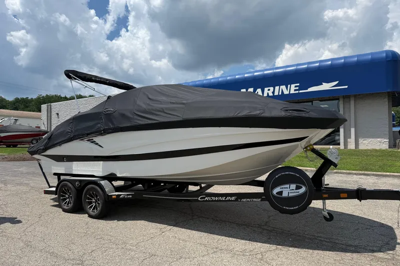 Slide: The Image of 2024 Crownline Eclipse E235 boat on trailer, covered, outside marine dealership. - 5